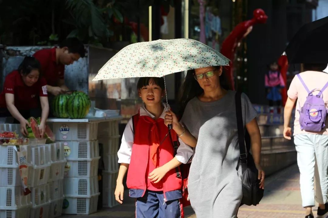 昨日,市民在阳光下打伞出行