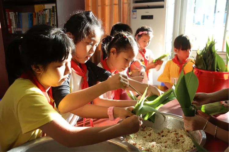 在学生们学习包粽子的同时,共建单位志愿者们为学生家长们讲解教育的