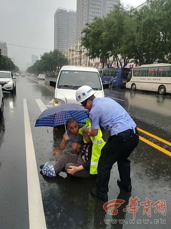 雨天老人过马路时被撞受伤 渭南交警撑雨衣遮雨