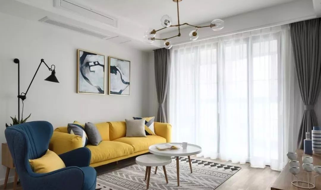 客厅以素色搭配明亮的黄色,简约舒适又充满活力,深蓝色沙发,吊灯,金色