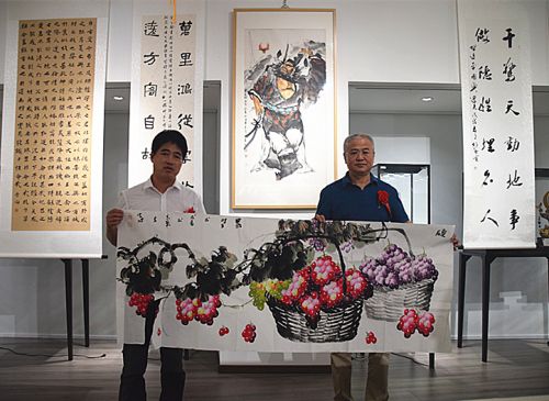 图为李俊旭(左)向参展嘉宾赠画