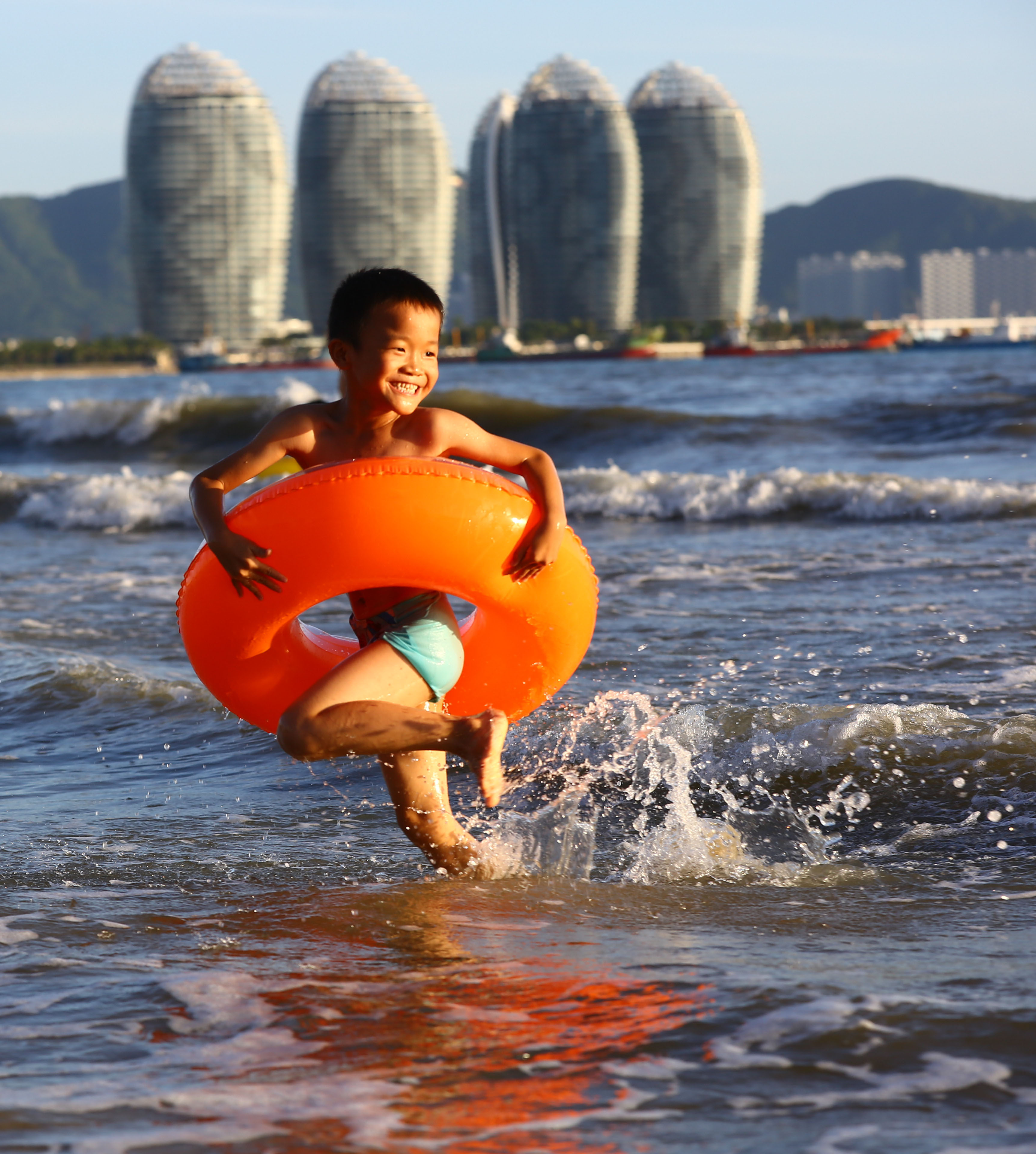 海南持续发布高温橙色预警,三亚市民纷纷来到海边戏水