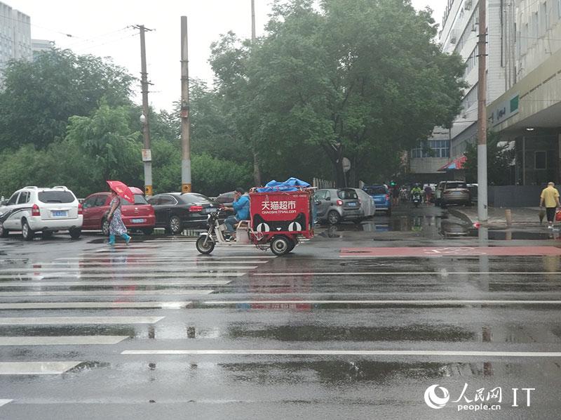 北京迎来强降雨快递小哥开启雨中送货模式