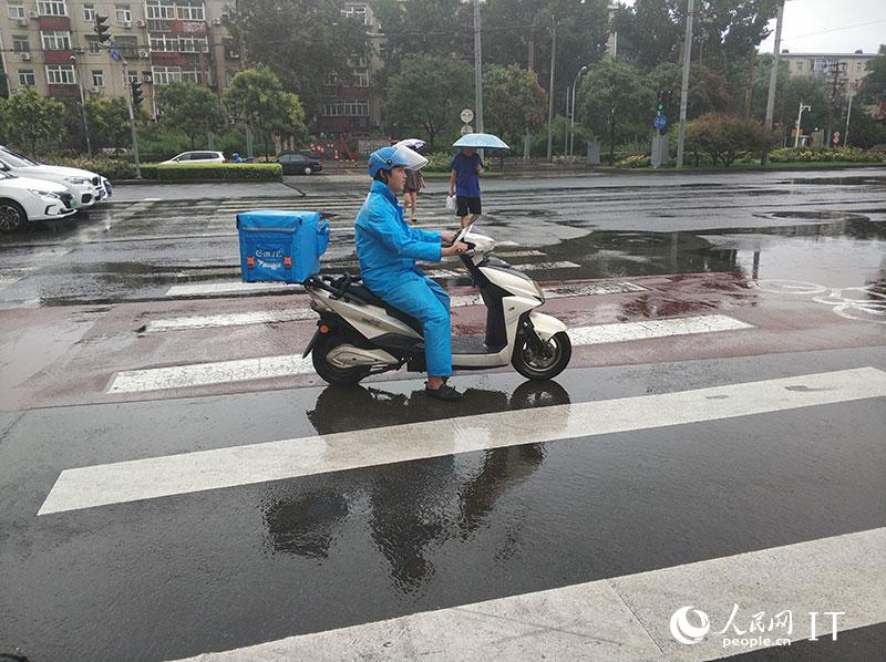 北京迎来强降雨快递小哥开启雨中送货模式