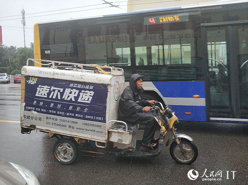 北京迎来强降雨快递小哥开启雨中送货模式