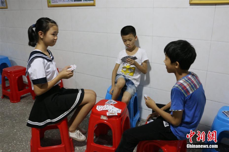 放暑假的小学生在洞内打牌避暑.林馨 摄