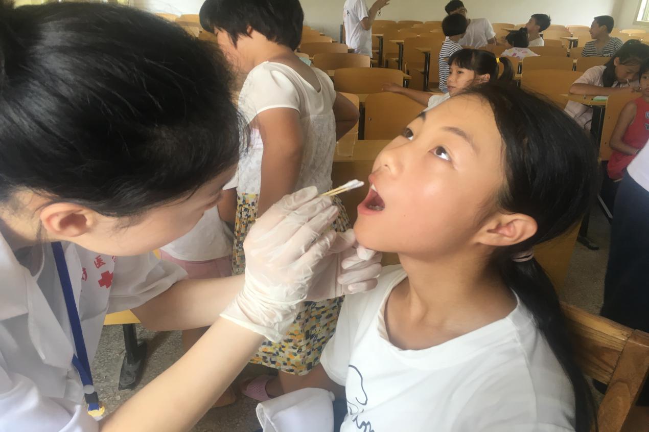 志愿者首先为孩子们检查牙齿以及清洁牙面,做好"涂氟"的第一步.