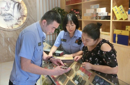 图为新津县烟草专卖局稽查人员向卷烟零售户宣传烟草专卖法律法规知识