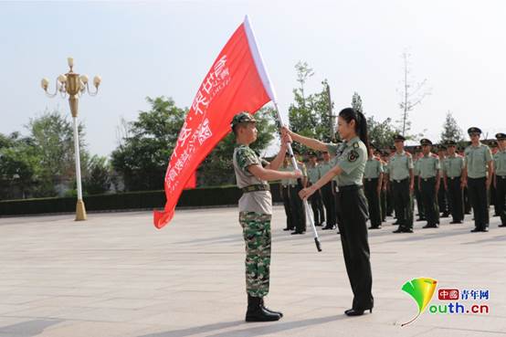 卫晨霞大校(右一)将队旗交给参与此次活动的代表李岩奇.资料图