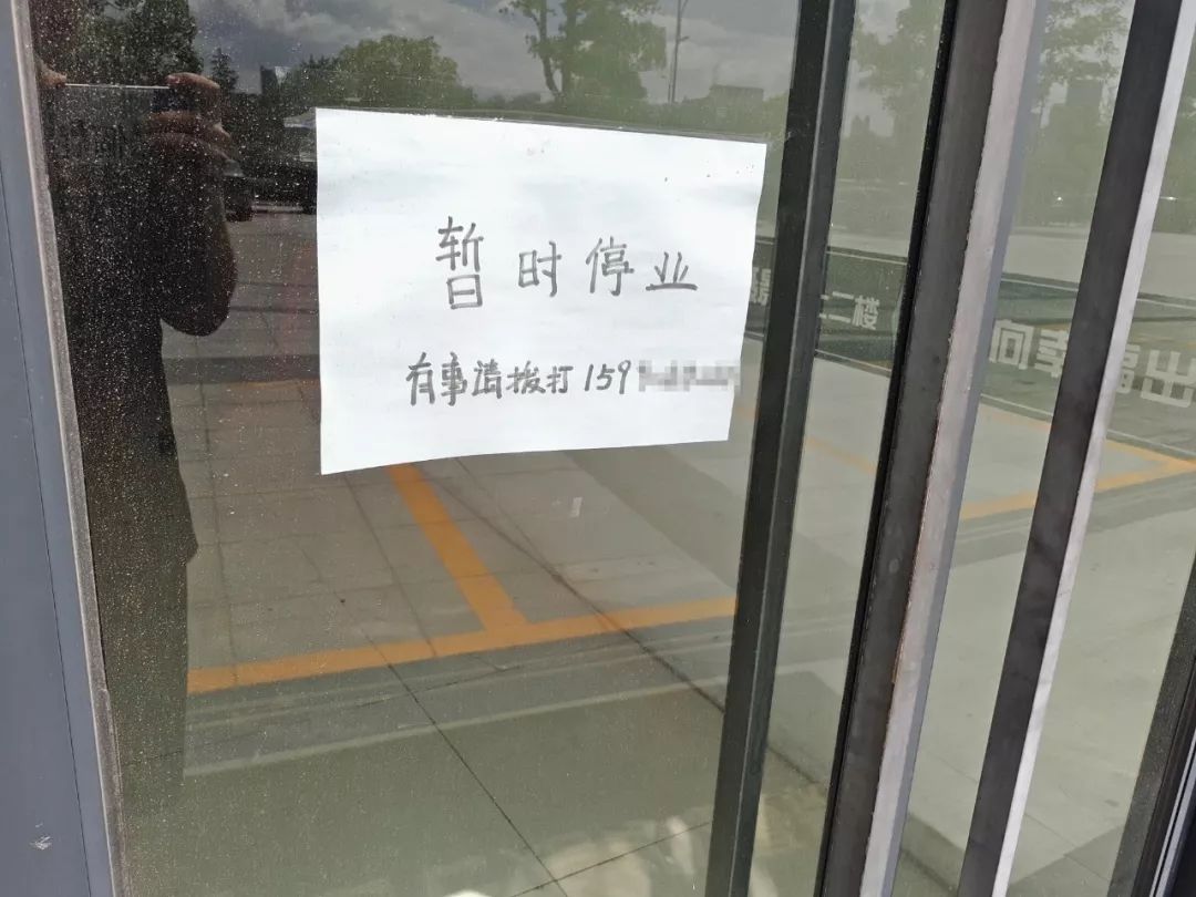 大门口的玻璃门上贴着一张纸,写着:「 暂时停业,有事请拨打xxx」.