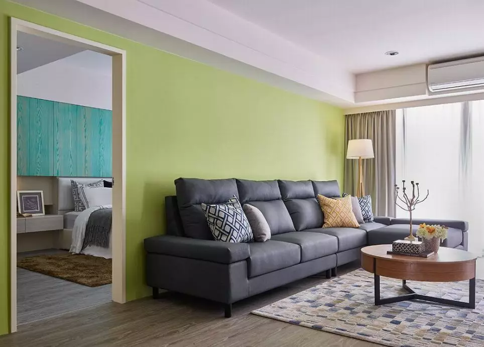 客厅简约开阔,草绿色的沙发背景墙,纹理清晰的木地板,深灰色布艺沙发