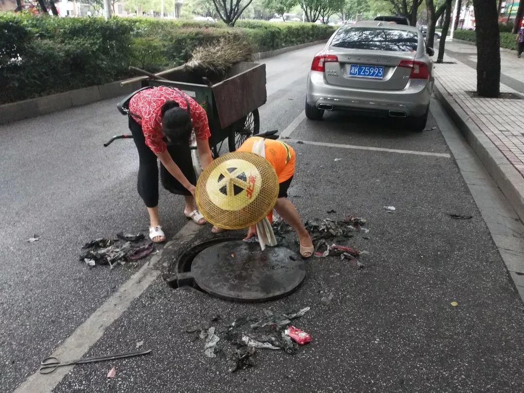 环卫工人清理暴雨后下水道污物