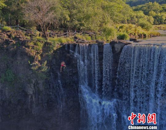 狄焕然沿着悬崖峭壁向上攀爬,准备登顶后第二次跳水 付丰羽 摄