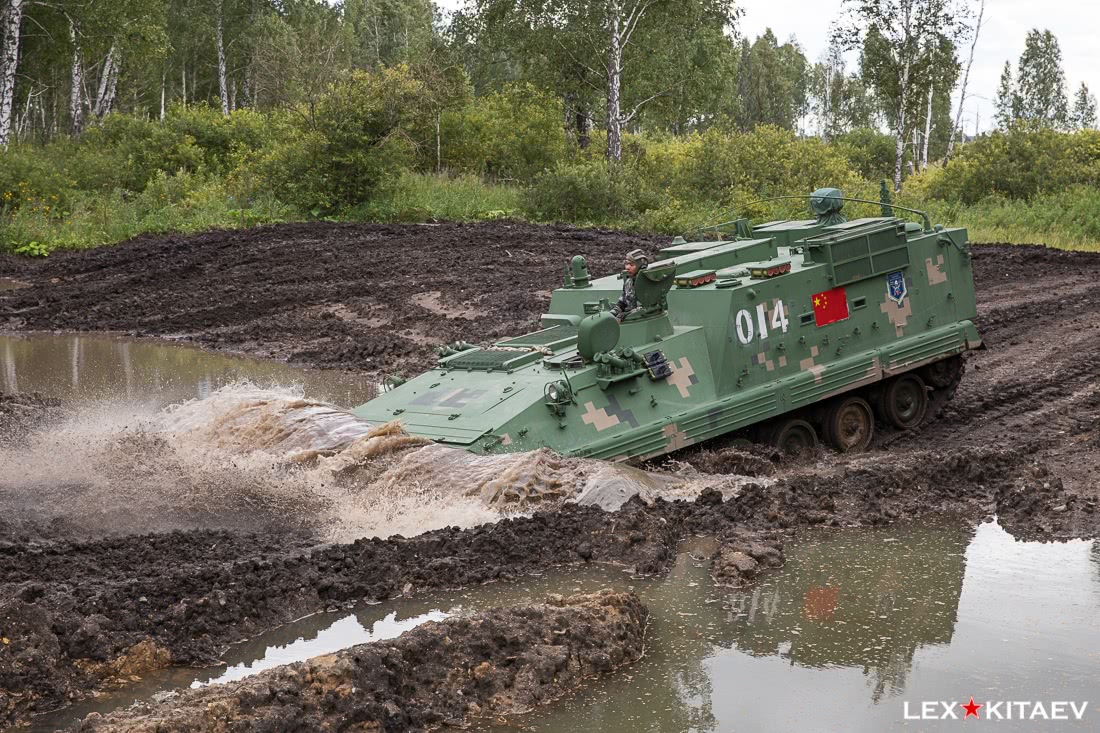 由于昨晚下雨,解放军履带式装甲指挥侦察车快速驶过路中间的水坑