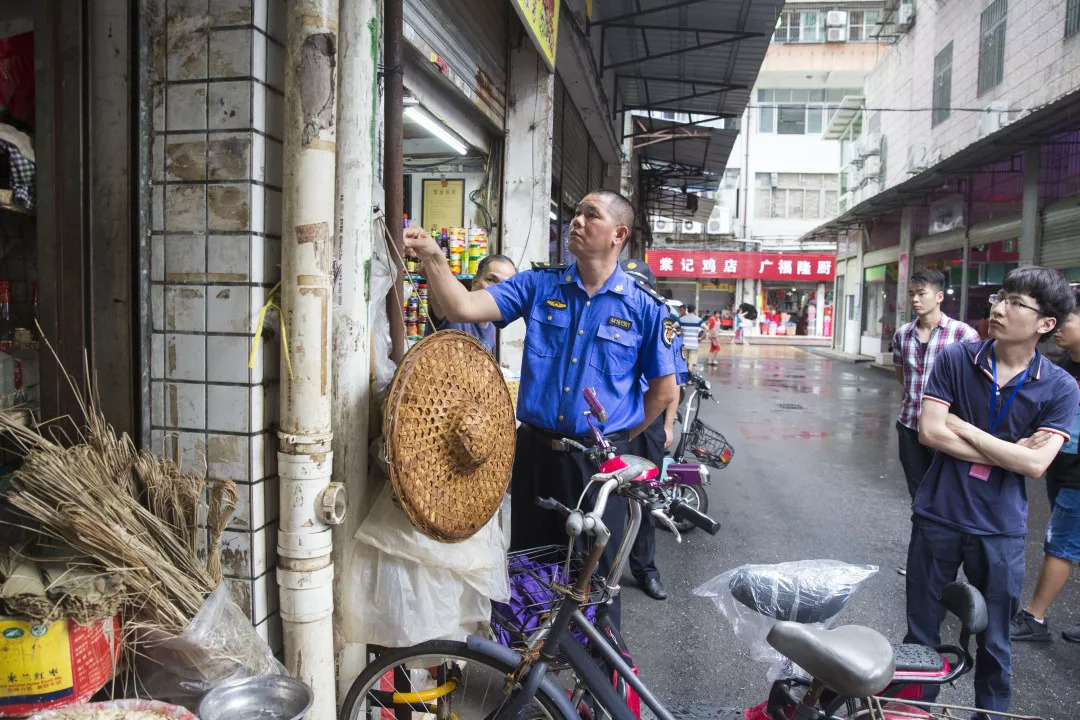 8月31日,城管人员查看摆放在店铺外的物品. 清远日报记者 李思靖 摄