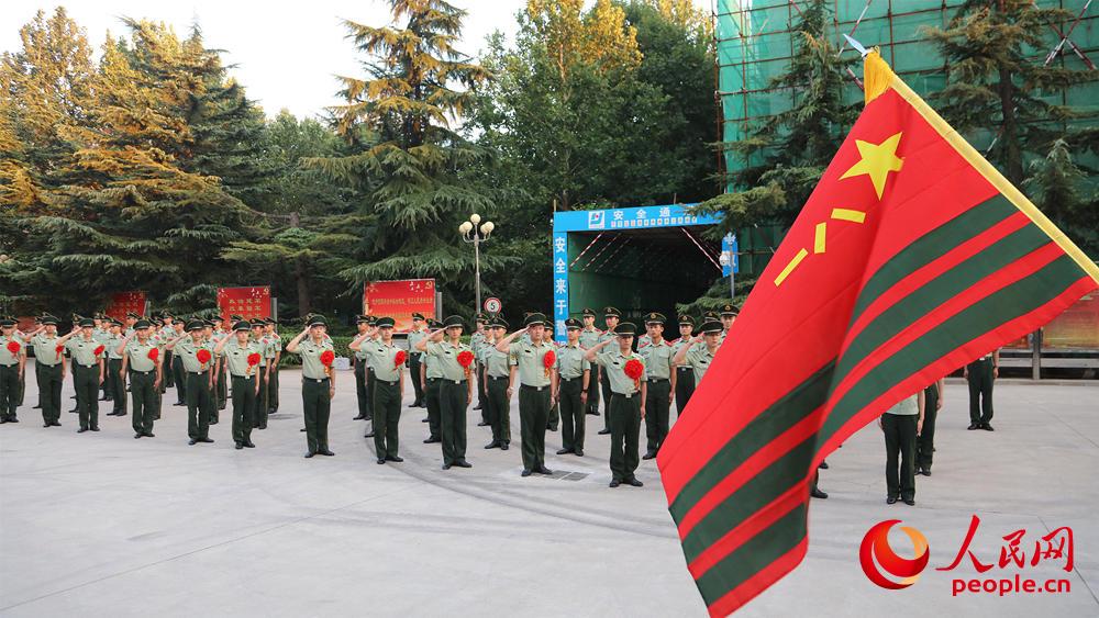 随着一声"立正,迎武警部队旗"口令的下达,三名护旗手迈着整齐的步伐