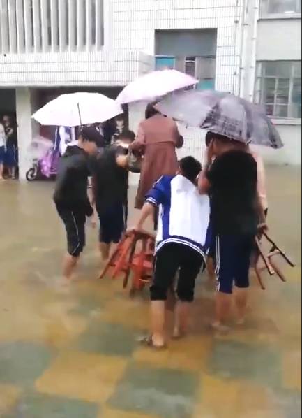 微博大v发布一段视频,内容是多名身穿郯城二中校服的男生冒雨手持板凳