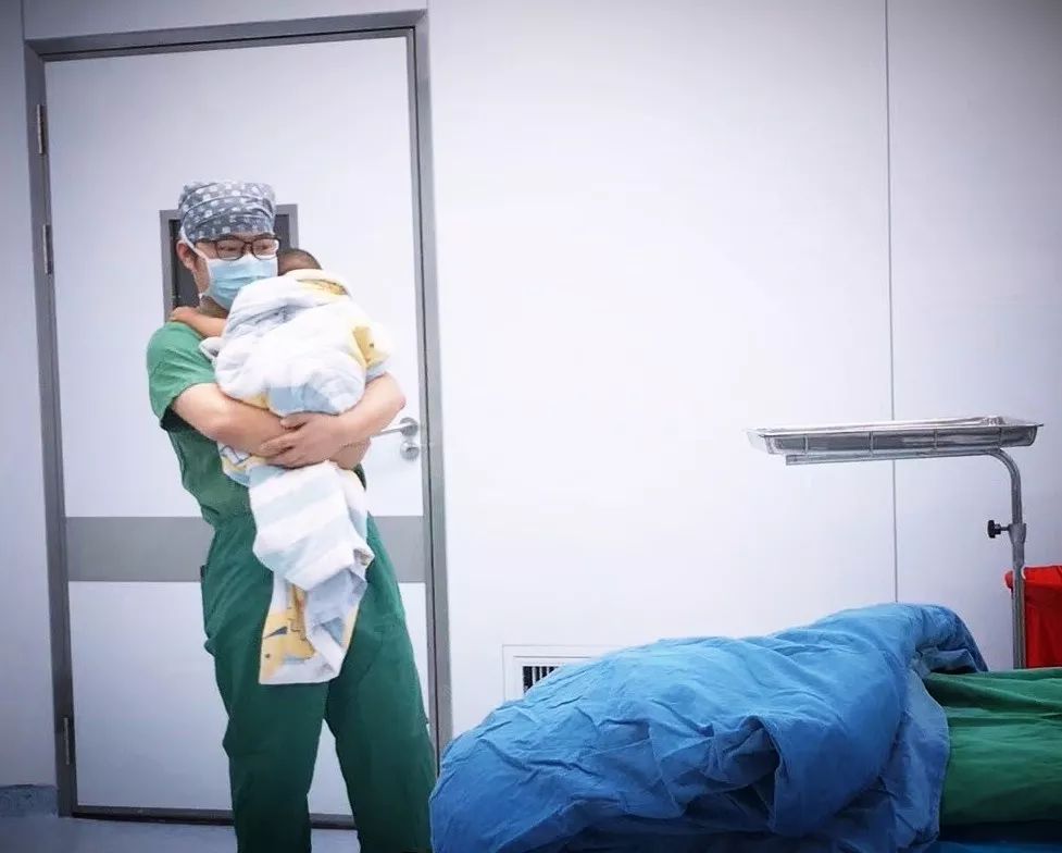 手术室里,这位年轻医生怀抱患儿的照片,让人看了好感动!