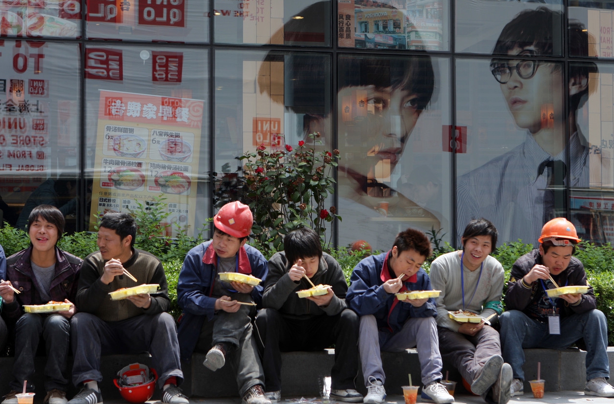 上海,农民工坐在路边吃饭.