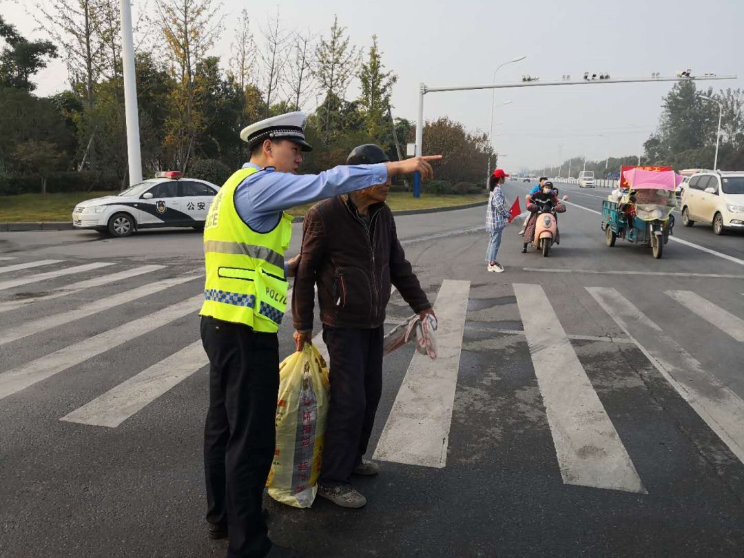 (执勤交警护送腿脚不便的老人过马路)