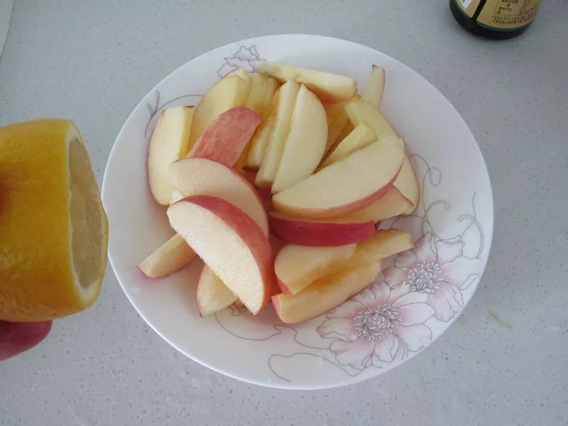 4,进微波炉的同时把苹果洗净切成均匀的片后挤入柠檬汁拌匀增味和防止