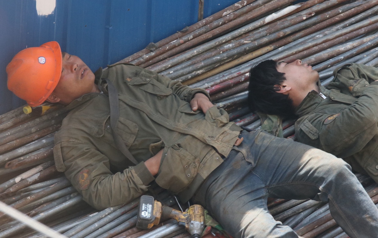 图为武汉市一建筑工地上 农民工 中午在钢管堆上睡熟了!
