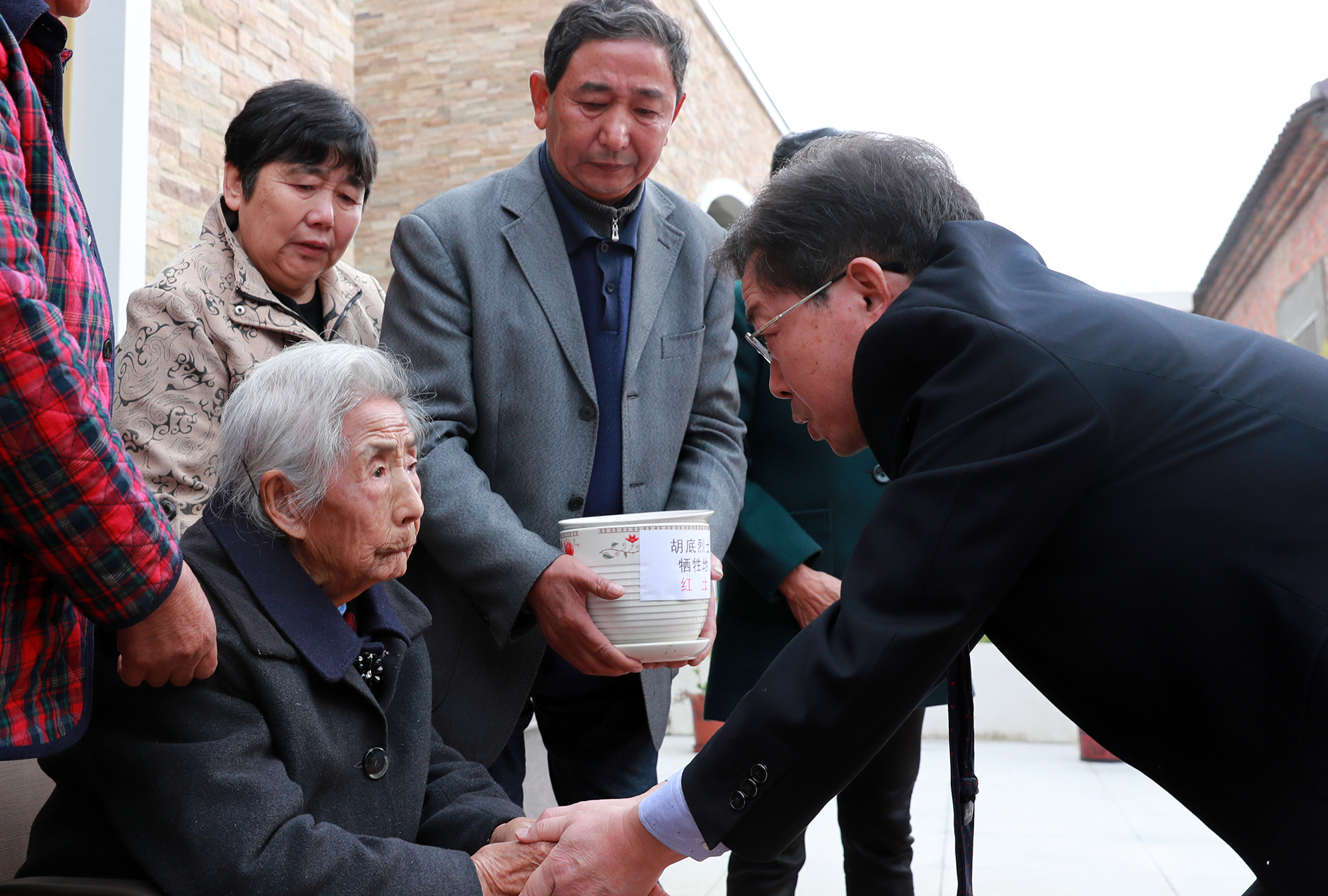 记者以跪拜礼节,向高龄老人转交其烈士哥哥牺牲地"红土"