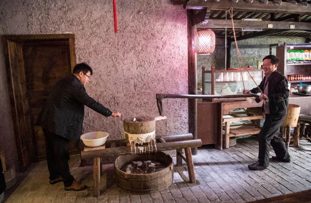 游客在作坊小镇的豆腐坊体验手工磨豆浆(11月7日摄).