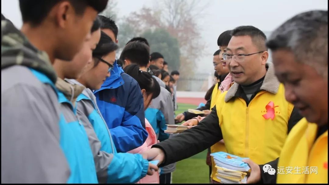 图为远安县卫生和计划生育局党组书记,局长何怀林为同学们发放宣传