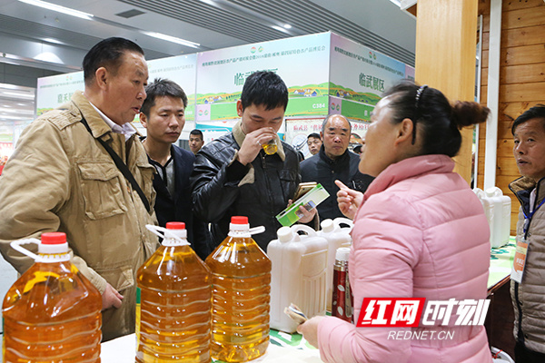 参展商向市民介绍"林富山茶油"的物理压榨制作经过.