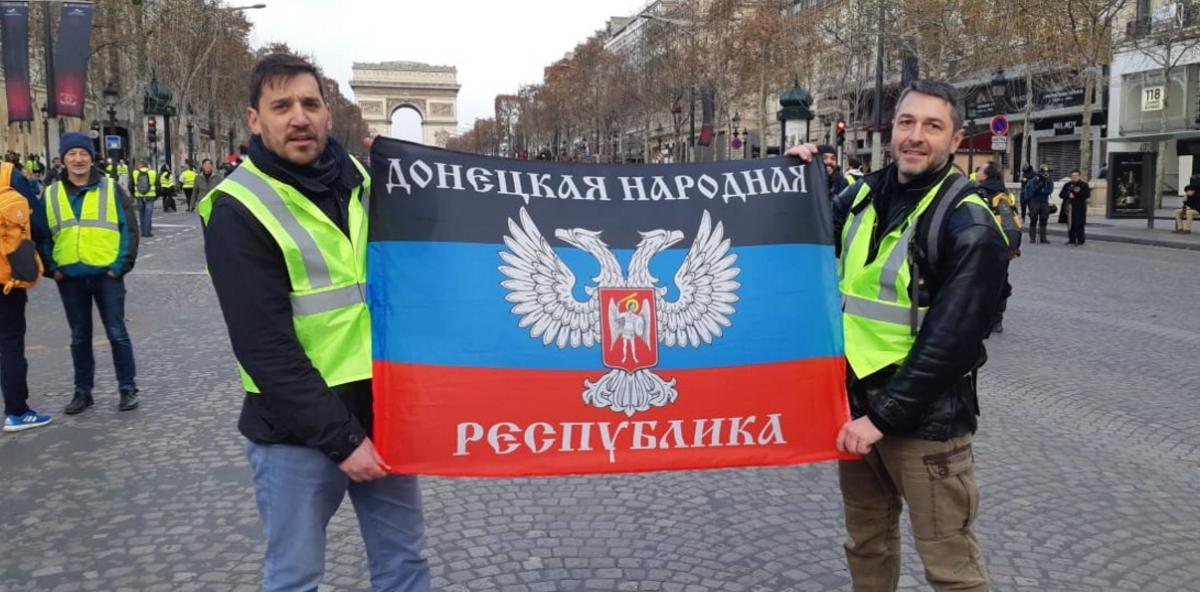 两名身穿"黄背心"的人手持自行宣布独立的"顿涅茨克人民共和国"旗帜