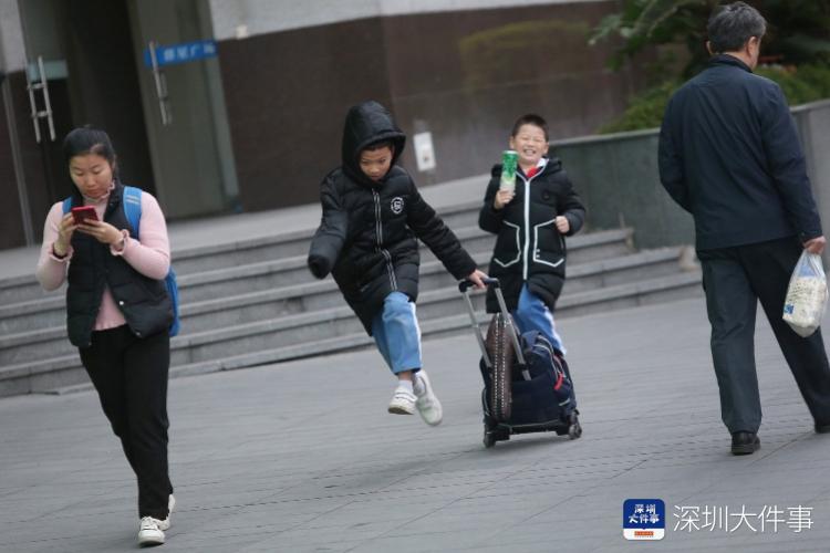 12月13日,深圳华新地铁站附近,穿着棉衣在路上奔跑的小学生.