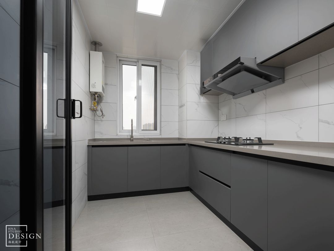 厨房整体选用灰色定制橱柜,配合大理石纹理墙砖强化简约质感.
