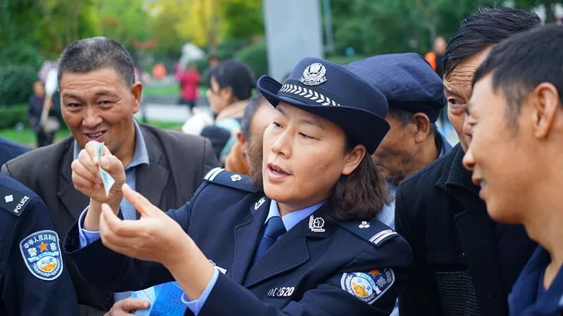 民警着99式新警服中的常服向群众讲解防范假钞知识