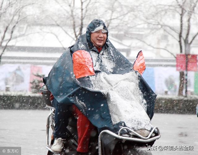 家长冒着大雪,骑电动车送孩子上学.这个雨伞打的好像不行啊!