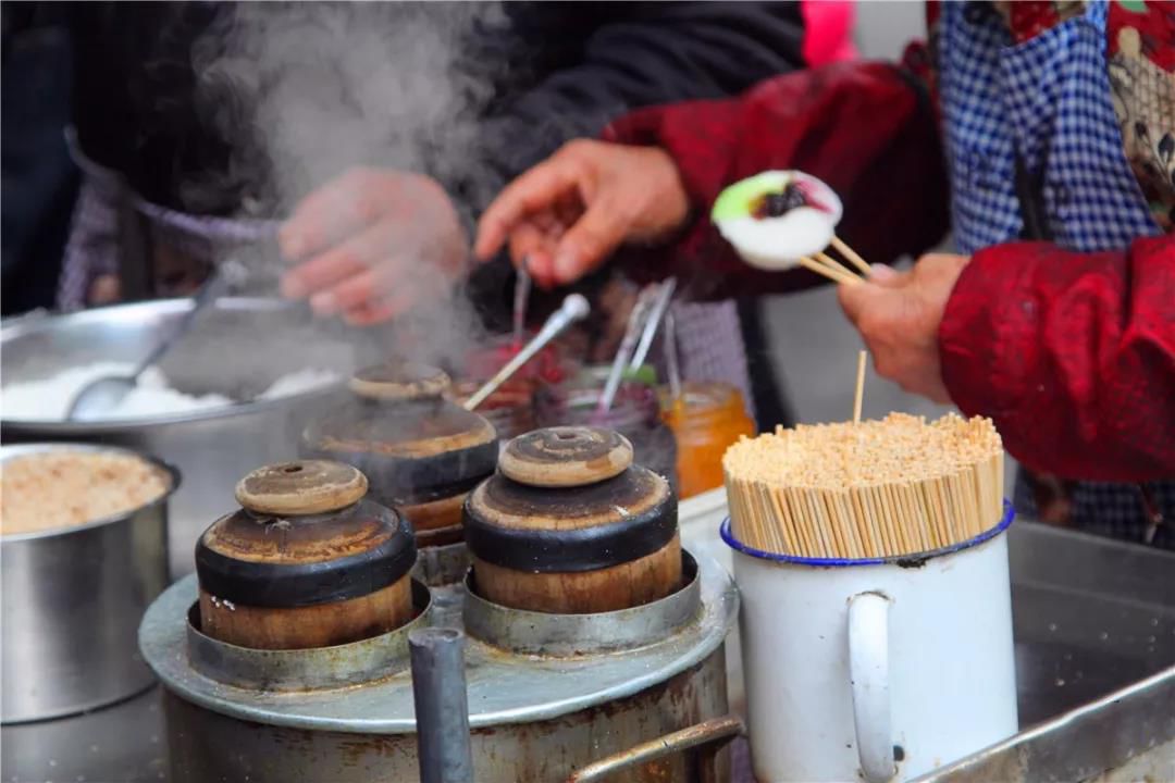 一个人舀米糕,另一个人负责蘸糖浆.五彩缤纷的颜色,看着都好看.