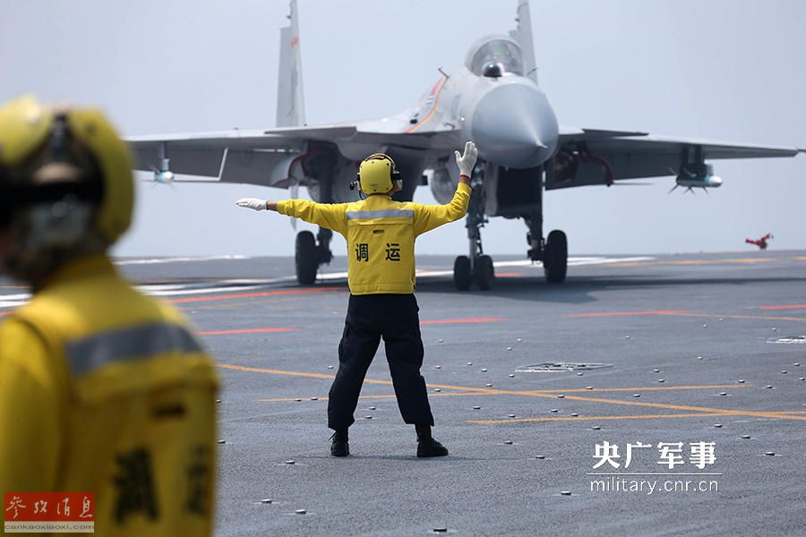 图为辽宁舰地勤人员在指挥歼-15战机在甲板上滑行.(央广军事 供图).