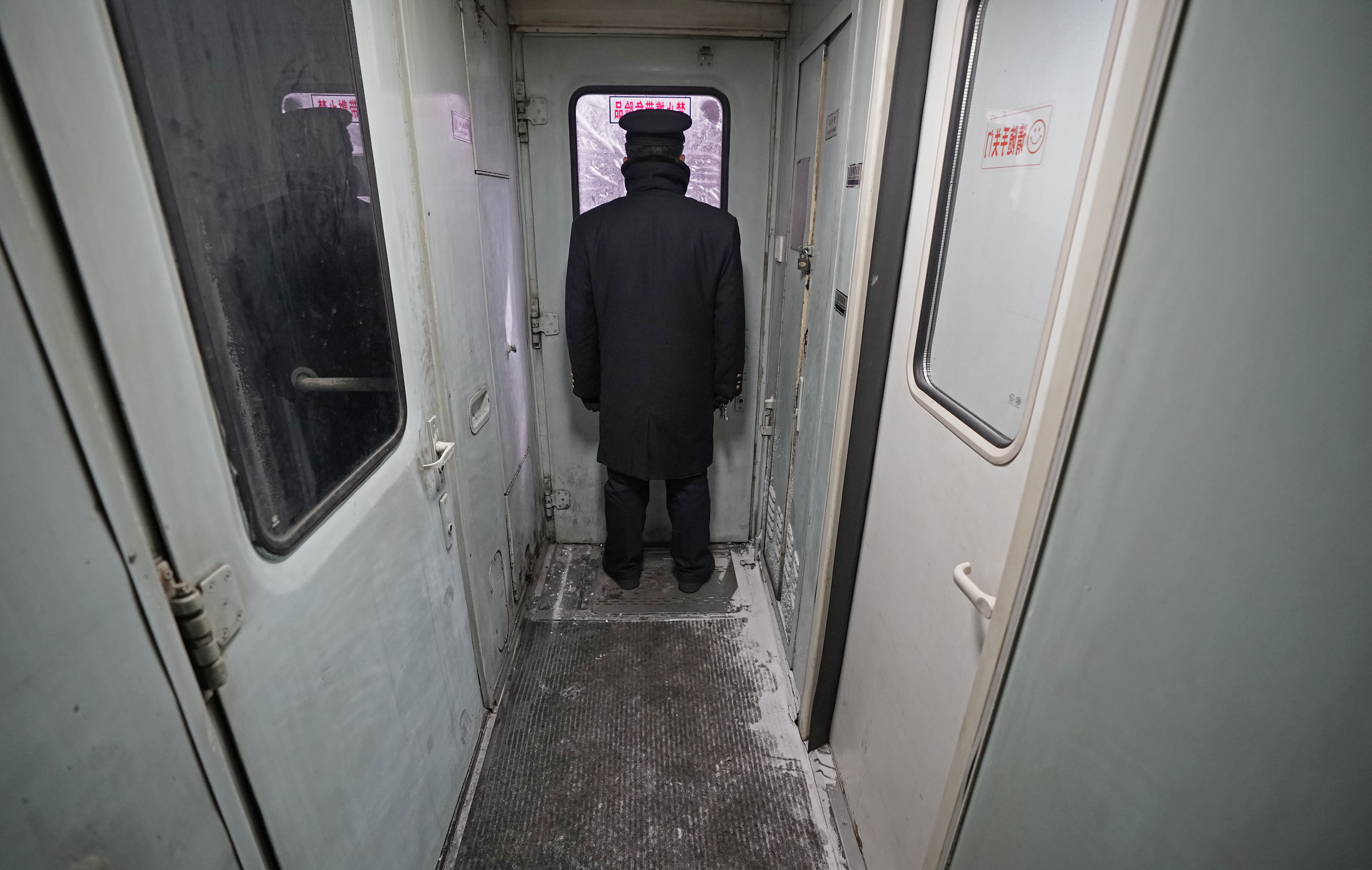 在齐齐哈尔开往古莲的6245次列车上,列车员在满是冰霜的车厢连接处