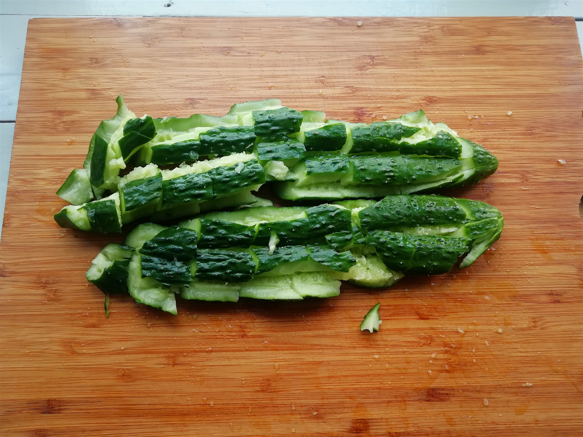 2.将黄瓜放在菜板上,用刀背将黄瓜拍裂,在将黄瓜切成段.