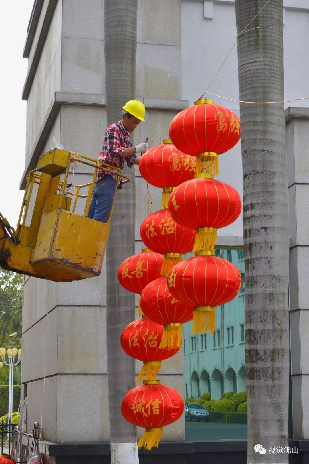 工人在高明区人民政府门口张挂灯笼.