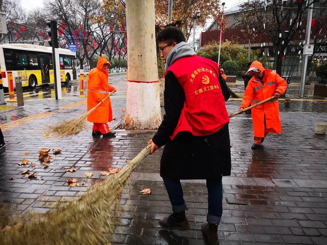 保洁组的志愿者在协助环卫工人清扫大街