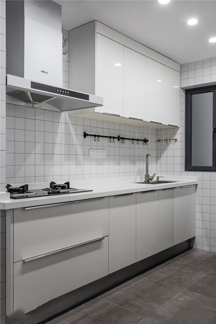 厨房白色的橱柜,黑灰色的地面和方格子白色墙砖搭配,简单整洁.