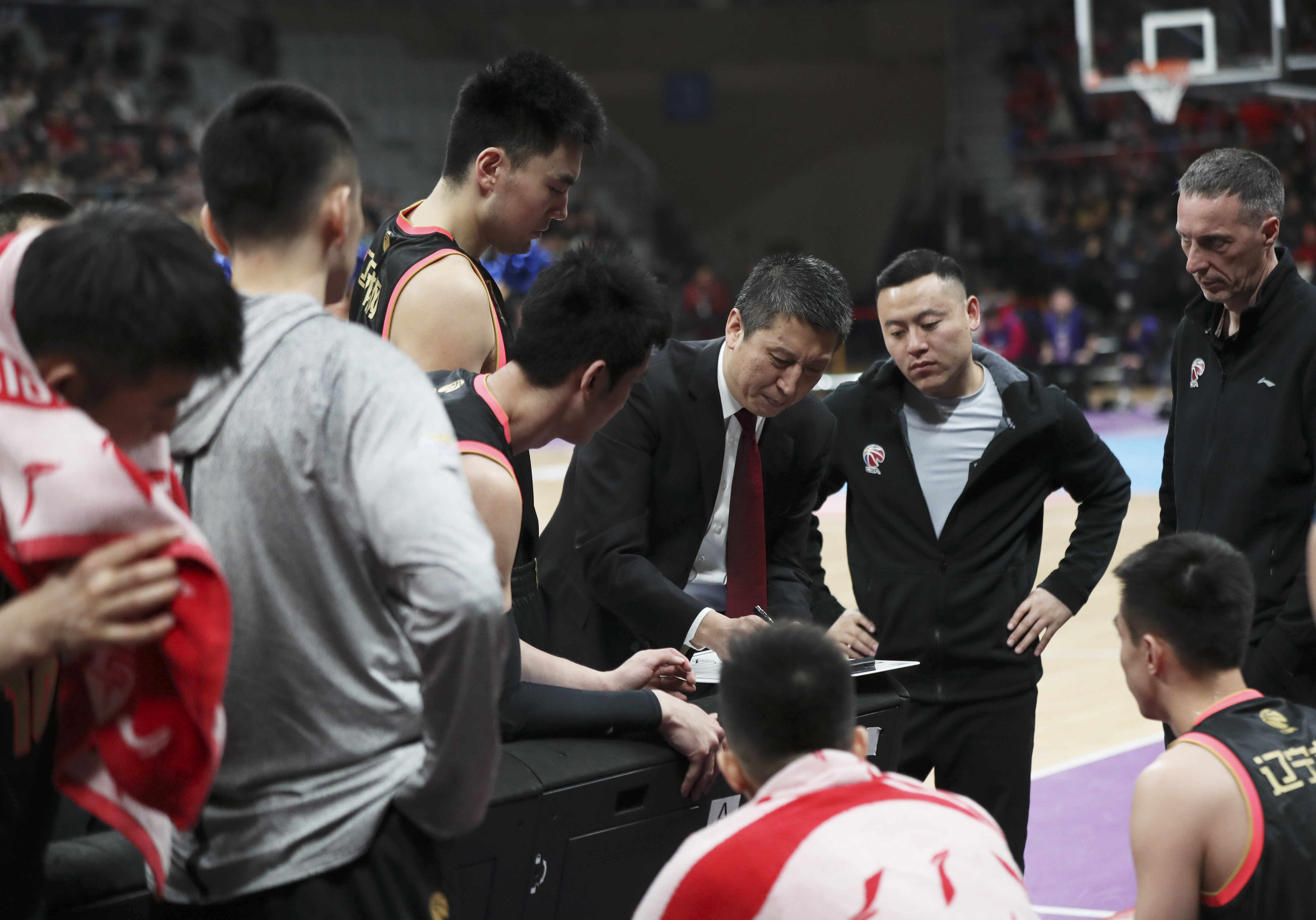 3月13日,辽宁本钢队主教练郭士强(上右三)在比赛间隙指导球员.