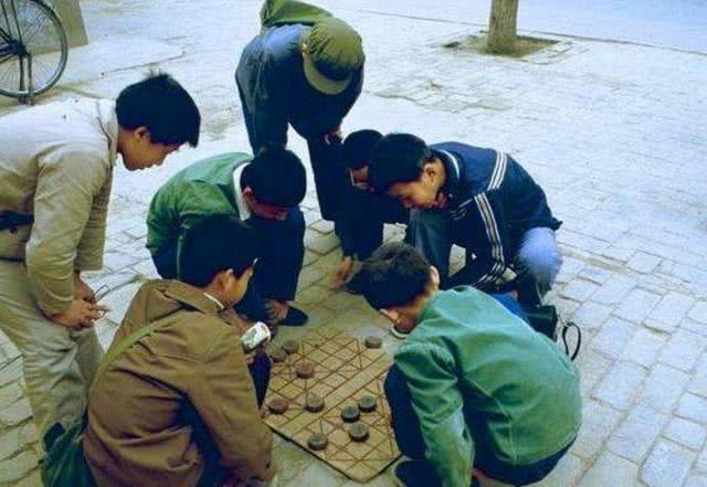 图为一群小男孩在地上下象棋,果然老棋手都是从小养成的