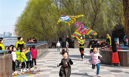 兰州一家幼儿园的老师指导孩子们在黄河风情线上放风筝