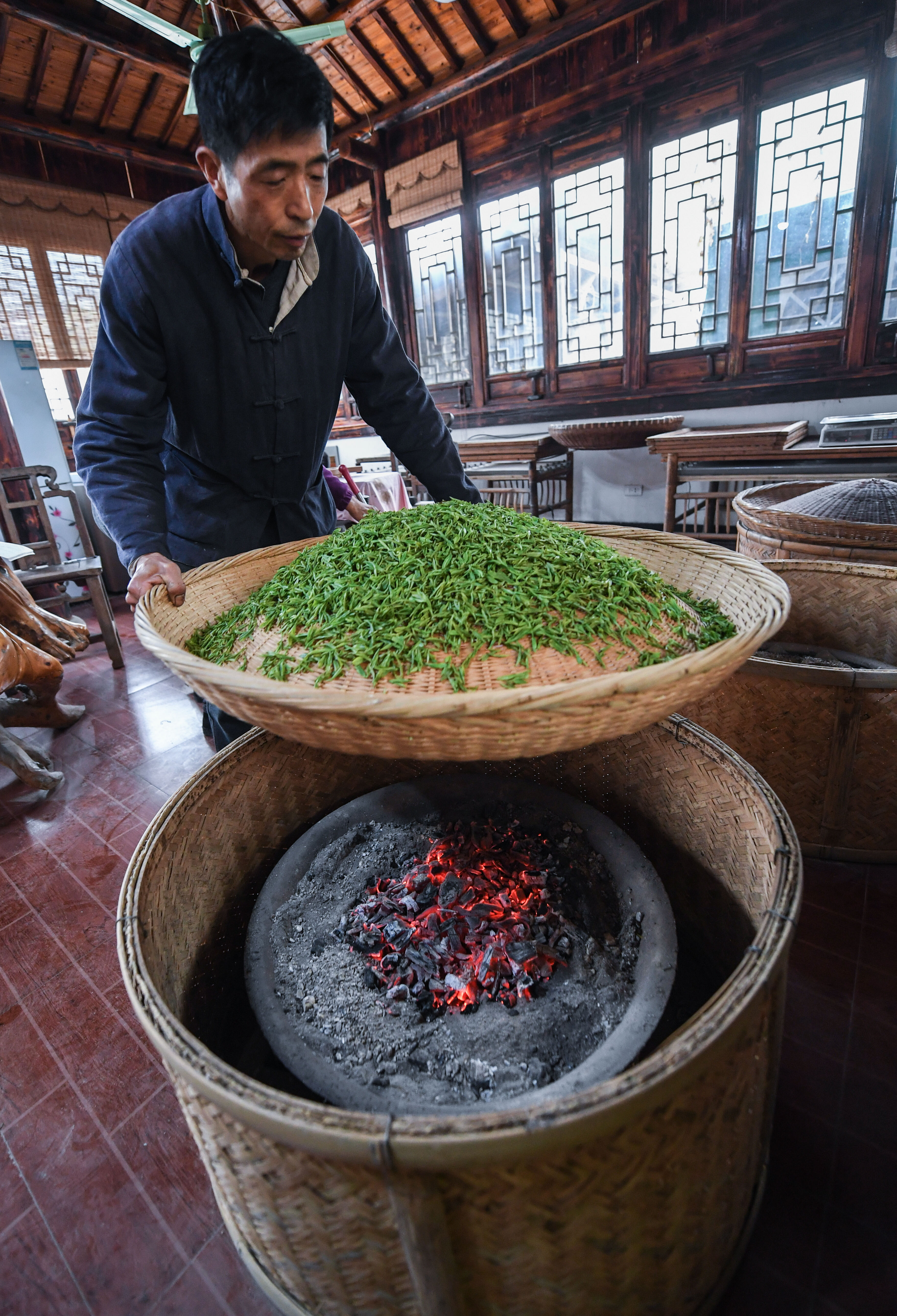 4月3日,郑福年把蒸好的紫笋茶放在竹匾上,下面放置炭火,进行初步烘干.