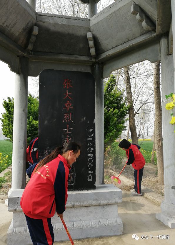 几位同学怀着崇敬的心情把张大卓烈士墓碑的周围清扫干净.