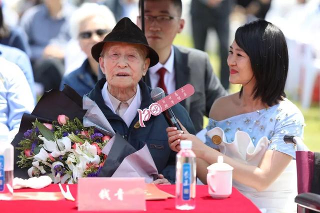 郑师右同学向最年长的校友103岁的抗战老兵钱青老先生献上校徽及鲜花