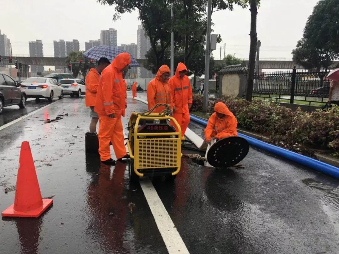 ▼环卫工人在雨中清理下水道口.图/田海