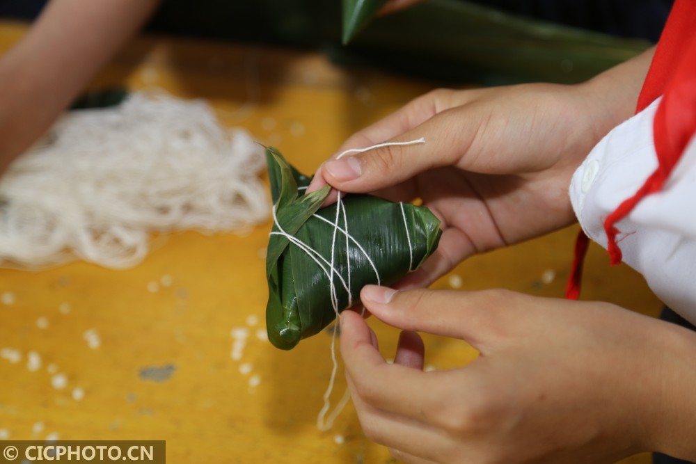 河北省平乡县县直第三小学老师在指导学生一起包粽子